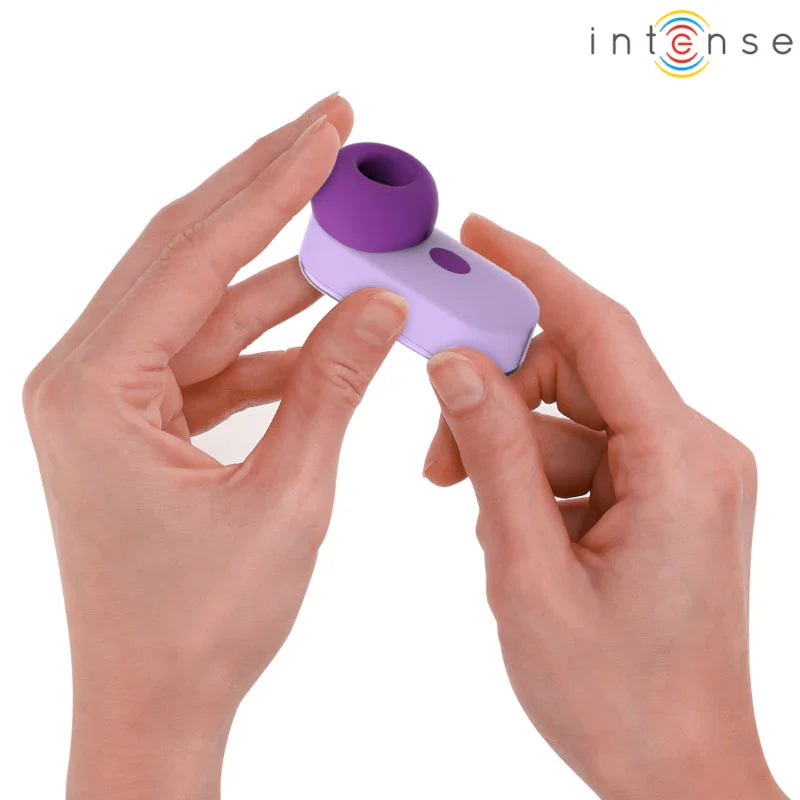 Estimulador de clítoris morado compacto, manos ajustando el accesorio sobre la base.