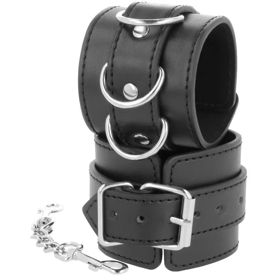Esposas de tobillo de cuero negro con correas, hebilla rectangular y cadena plateada.